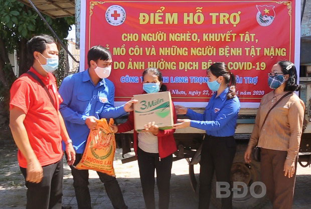 Ông Nguyễn Văn Tri (áo đỏ,bên trái) trao tặng quà hỗ trợ người dân bị ảnh hưởng bởi dịch Covid-19