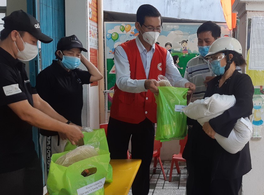 Ông Lê Phong - Phó Chủ tịch Thường trực Hội CTĐ tỉnh (áo đỏ) đang trao hỗ trợ cho người dân khu vực 3, phường Hải Cảng, Tp. Quy Nhơn