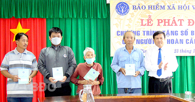 Giám đốc BHXH tỉnh Võ Năm trao thẻ BHYT cho học sinh có hoàn cảnh khó khăn ở TP Quy Nhơn. Ảnh: N.M